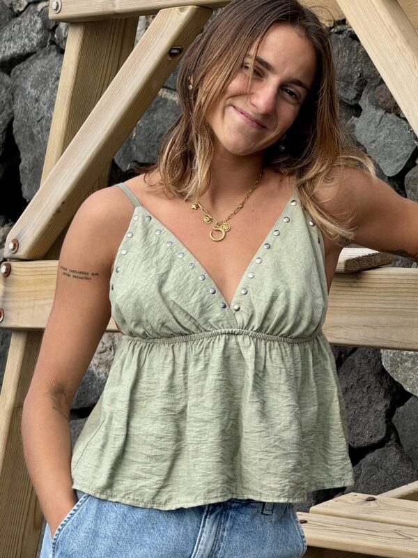 Mujer sonriendo con el Top Ibiza verde con tachuelas de Sal y Lava en exteriores